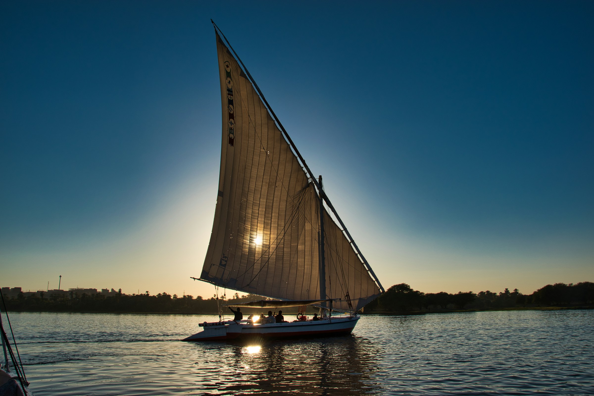 A felucca under sail on the Nile at Aswan, low sun on the water